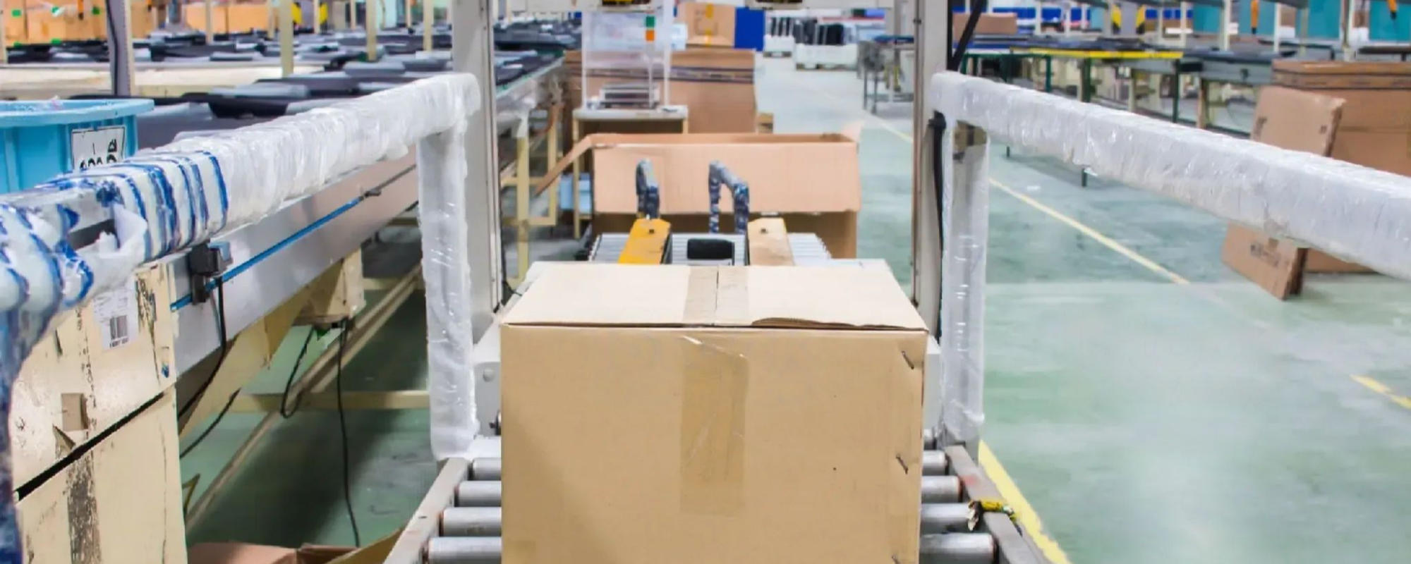 Automatyzacja pakowania. Opakowanie zbiorcze na taśmociągu w fabryce FMCG.