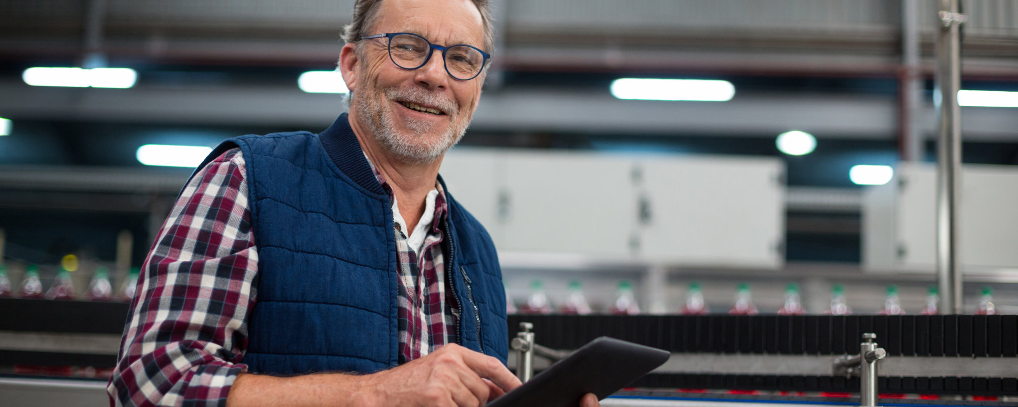 Banner. Man in mid age, smart, in glases, with a notepad, supervising production line.